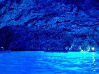 Crystal-clear azure waters surround the enchanting sea cave, revealing a mesmerizing play of light and shadow.