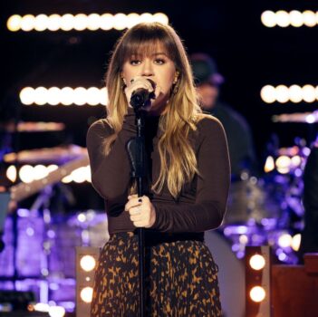 Kelly Clarkson, American singer, songwriter, and television personality, performing on stage with a microphone in hand, showcasing her powerful vocals and engaging stage presence.